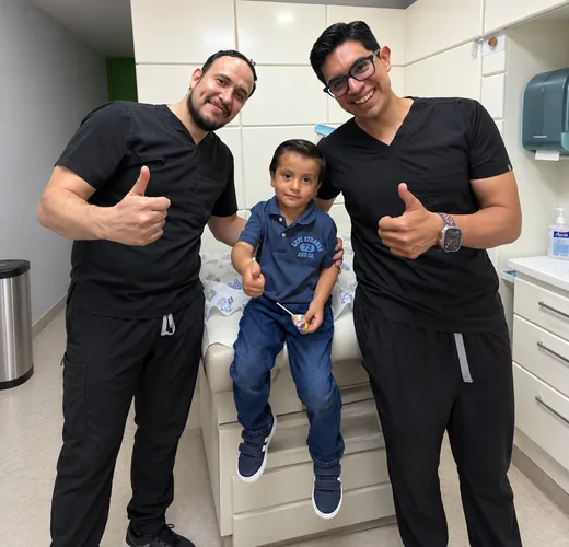 Dos cirujanos pediatras del Centro CUP con un paciente tras su cirugía, en el consultorio